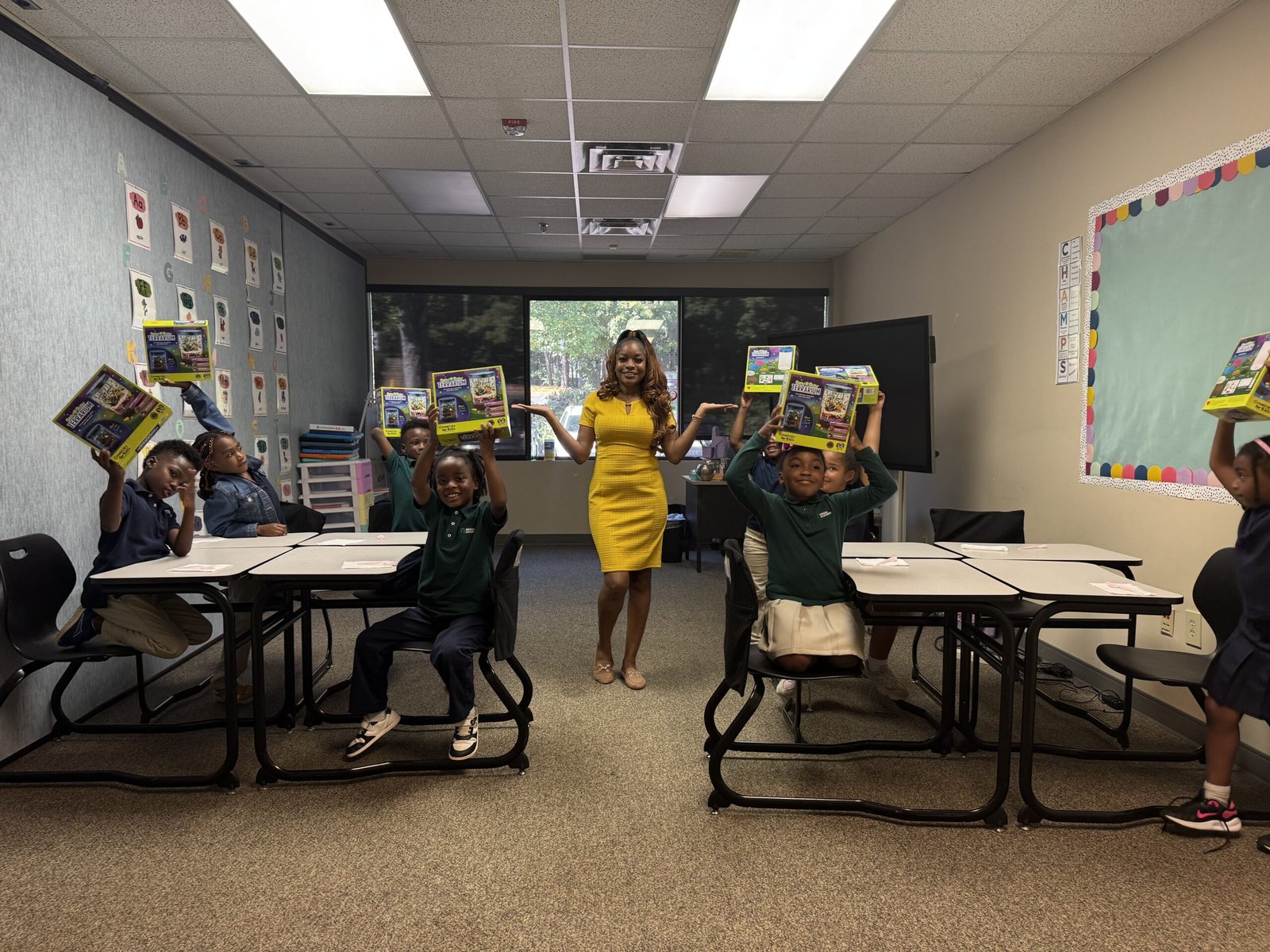 Ms. Nathan with students holding up their activity kits in a classroom